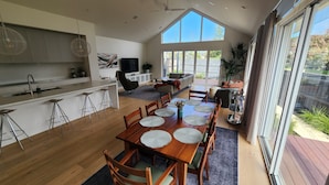 A modern kitchen with a dining area, large windows, and a view of the outdoors. - Luxury Coastal Townhouse Mornington (Mornington)