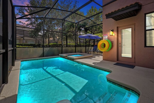 Une piscine extérieure dotée d’une structure en verre, d’une porte et d’un parasol bleu.