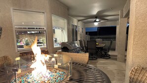 A patio area with a glass table featuring a fire feature, wicker furniture, a grill, and a ceiling fan. - Hav-A-Time! Pet Friendly Pool House w/ Game Room! (Lake Havasu City)