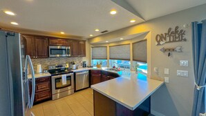 A modern kitchen with stainless steel appliances, wooden cabinets, and a large island. - Hav-A-Time! Pet Friendly Pool House w/ Game Room! (Lake Havasu City)
