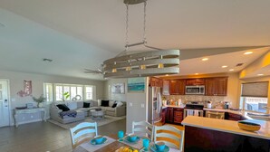 A spacious living area with a dining table set for six, a kitchen with modern appliances, and a ceiling fan. - Hav-A-Time! Pet Friendly Pool House w/ Game Room! (Lake Havasu City)