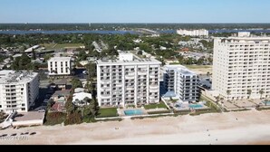 Un paisaje urbano costero con varios edificios altos, una playa y un puerto deportivo.