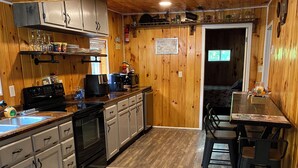 Un intérieur en bois comprenant un espace cuisine équipé de placards, d’une cuisinière et d’une table à manger avec des chaises.