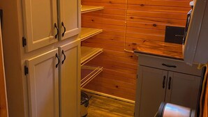 Une cuisine de taille réduite avec des murs en bois, une fenêtre et une poubelle.