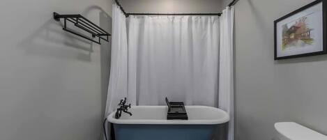 Een badkamer met een pootbad, toilet en douchegordijn.