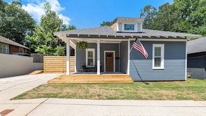 A two-story house with a porch, a flag, and a small garden area.