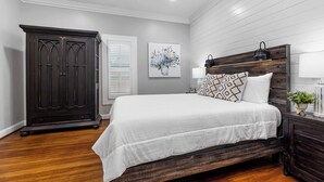 A bedroom with a wooden bed frame, a dark wardrobe, and a ceiling fan.