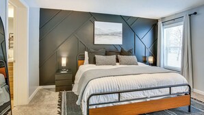 A modern bedroom with a bed, bedside tables, a nightstand, and a large window with curtains. - Pine River Ranch-17 Acre Outdoor Paradise in the heart of the Manistee Forest (Wellston)