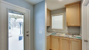 A kitchen with wooden cabinets, a marble countertop, and a window with blinds. - Pine River Ranch-17 Acre Outdoor Paradise in the heart of the Manistee Forest (Wellston)