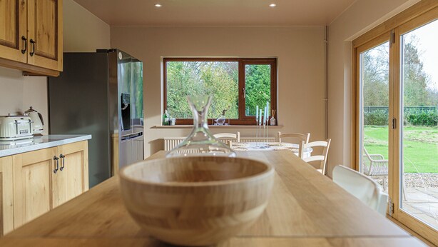 Een keuken met houten kastjes, een groot raam en een eettafel met stoelen.