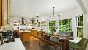 Une cuisine moderne dotée d’un îlot central, de meubles de rangement en bois et d’un coin repas avec une banquette et des chaises.