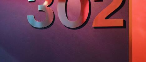 A wall with the number 302 in metallic letters.