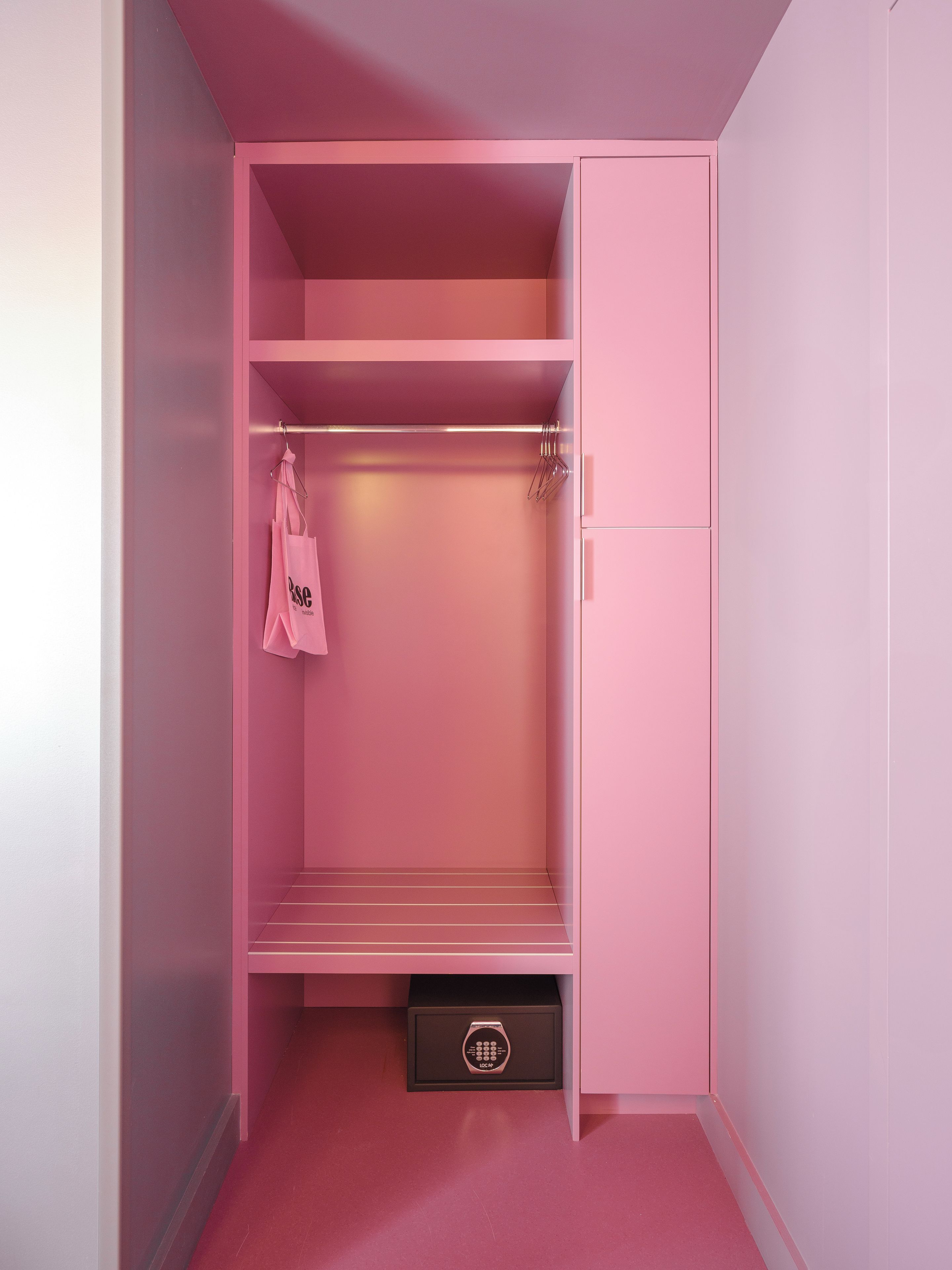 A pink wardrobe with a hanging rack and a storage box.