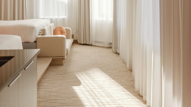 A modern hotel room with a large window, a sofa, a chair, and a desk. - Rose Hôtel Invisible (Québec)
