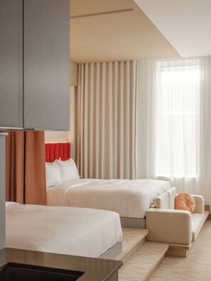 A hotel room with two beds, a sofa, and a desk.