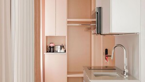 A compact kitchenette with a sink, a coffee maker, and a small countertop. - Rose Hôtel Invisible (Québec)