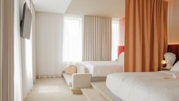 A hotel room with a large bed, a smaller bed, a sofa, and a television mounted on the wall.