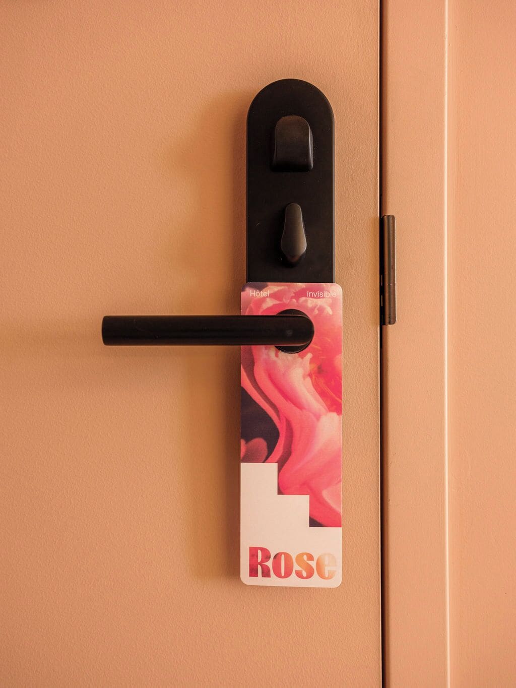 Una puerta con un picaporte negro y una tarjeta con la palabra 'ROSE'.