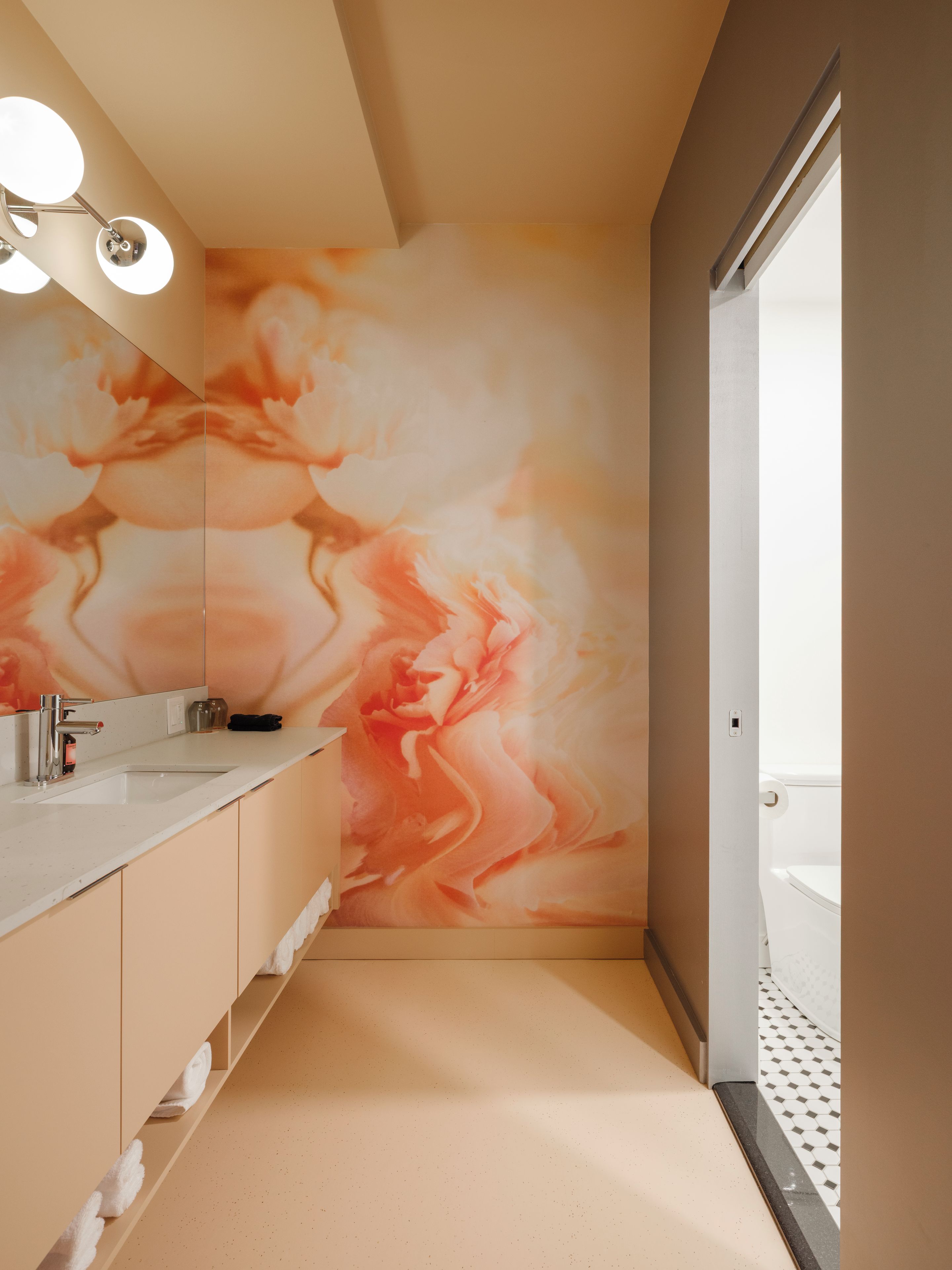 A modern bathroom with a large mirror, a sink, and a toilet.