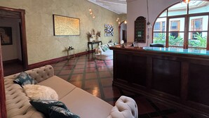 A spacious lobby with a billiards table, a sofa, and a large window offering a view of greenery. - The Victorian Hotel CR (San José)