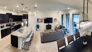 A modern kitchen with dark cabinets, a granite countertop, and stainless steel appliances. - Spacious 5-bedroom townhome in gated community. Minutes from Disney! Sleeps 10 (Davenport)