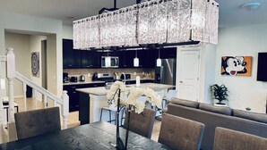 A modern kitchen with dark cabinets, stainless steel appliances, and a central island. - Spacious 5-bedroom townhome in gated community. Minutes from Disney! Sleeps 10 (Davenport)