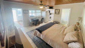 Une chambre avec un lit, un bureau et une kitchenette.