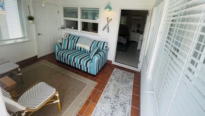 Une pièce avec un canapé à rayures, un ventilateur de plafond, une petite table et une chaise.