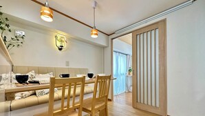Ein moderner Essbereich mit einem Holztisch, Stühlen und einer gepolsterten Bank, beleuchtet von Pendelleuchten.