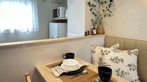 Eine kompakte Küchenzeile mit Mikrowelle und Kühlschrank, ein Essbereich mit Tisch für zwei Personen und ein Spiegel, der den Raum widergibt.