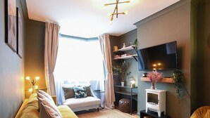 Una sala de estar acogedora con sofá, una mesita, televisor y chimenea.