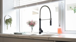Una cocina con un grifo moderno, una ventana con vistas y una pequeña planta en el alféizar.