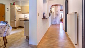 A modern kitchen with a refrigerator, stove, and sink. A dining table with chairs is in the foreground. - Zeitlos by Interhome (Reifnitz)