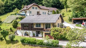 A two-story house with a sloped roof, surrounded by lush greenery and a hillside. - Zeitlos by Interhome (Reifnitz)