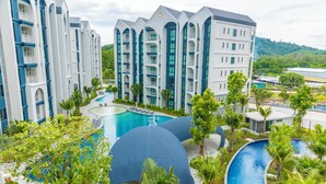 Un complexe hôtelier doté de plusieurs piscines, de palmiers et de bâtiments modernes avec balcons.