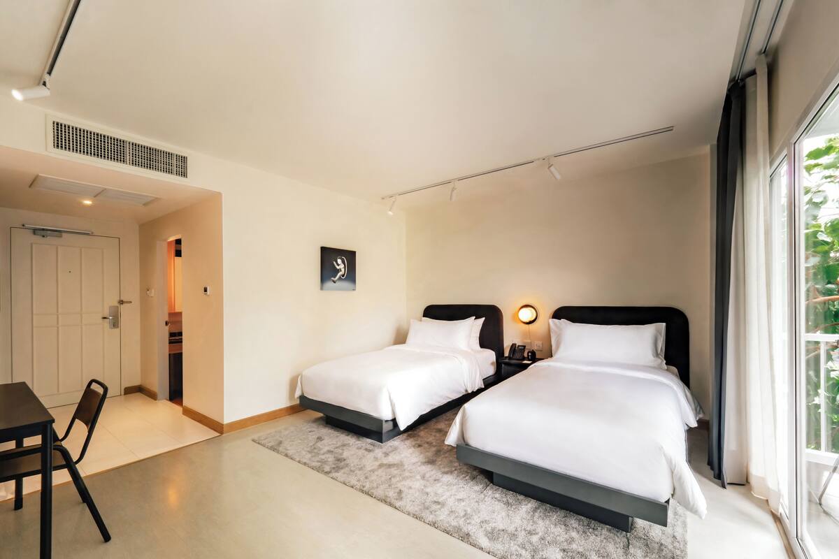 Ein Hotelzimmer mit zwei Betten, einem Schreibtisch und einem Stuhl.