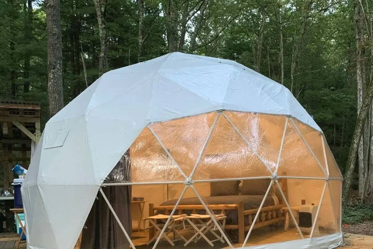 Eine geodätische Kuppel mit einem transparenten Bereich, der ein Interieur mit Tisch und Stühlen zeigt.