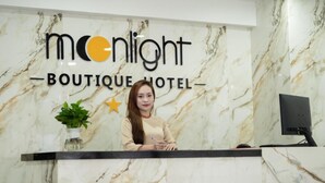 A reception desk with a marble wall background and a sign that reads "Moonlight Boutique Hotel". - Moonlight Boutique Hotel (Hue)