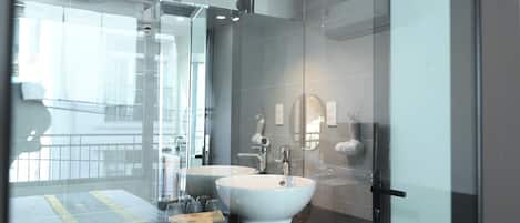 Un baño moderno con dos lavamanos, cabina de ducha de vidrio y un espejo grande.