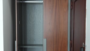 En walk-in-garderob med en skjutdörr, en träpanel och en hylla i metall.