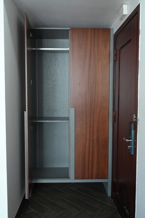 A walk-in closet with a sliding door, a wooden panel, and a metal shelf. - Moonlight Boutique Hotel (Hue)
