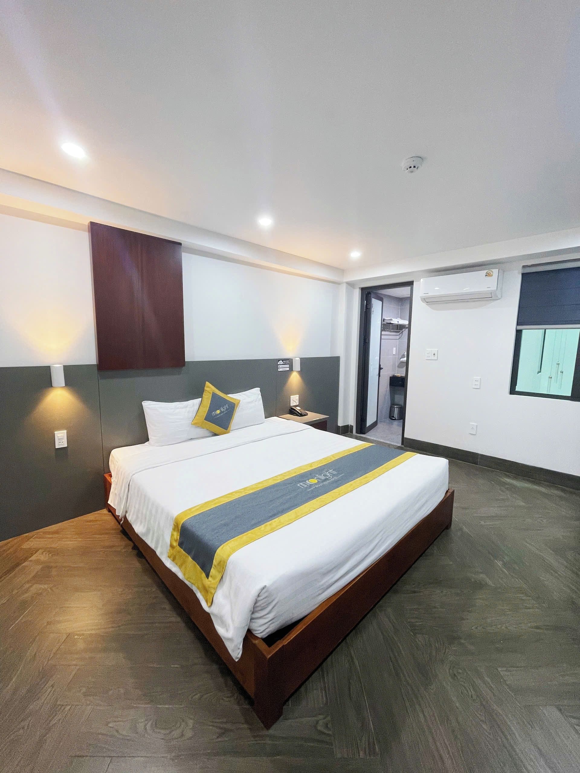 Habitación de hotel con una cama grande, mesitas de noche, equipo de aire acondicionado y vistas al exterior.
