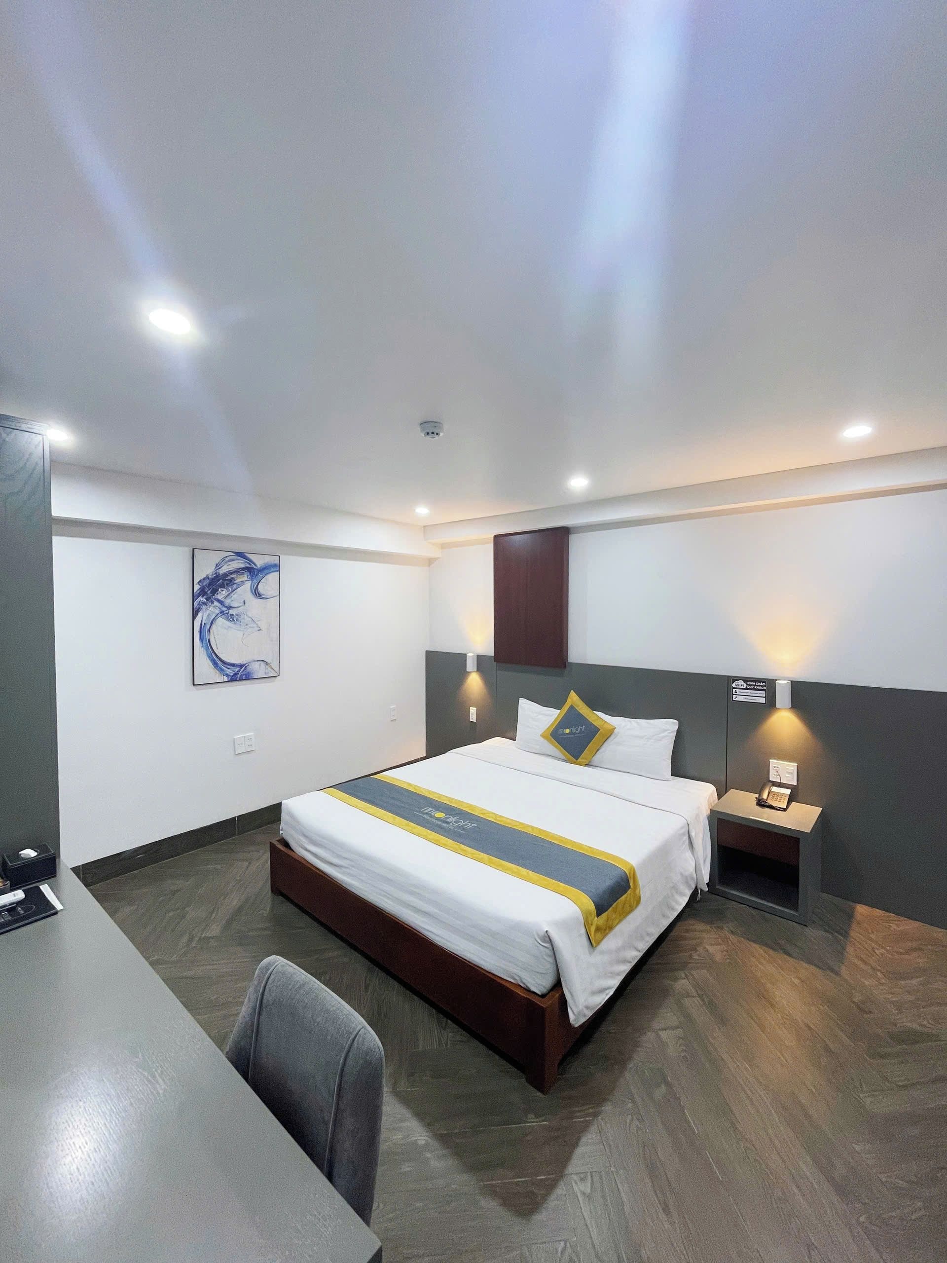 A hotel room with a bed, bedside tables, a desk, and a chair.