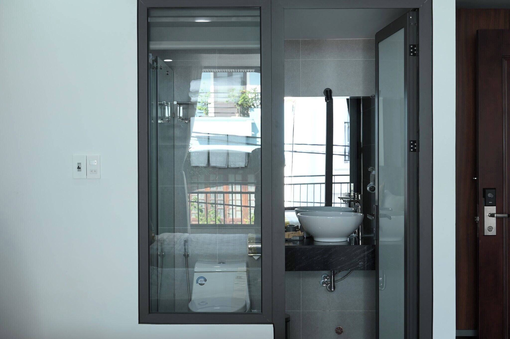 A modern bathroom with a glass-enclosed shower, a white sink, and a visible towel rack.
