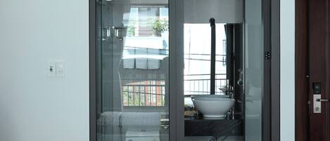 A modern bathroom with a glass-enclosed shower, a white sink, and a visible towel rack.