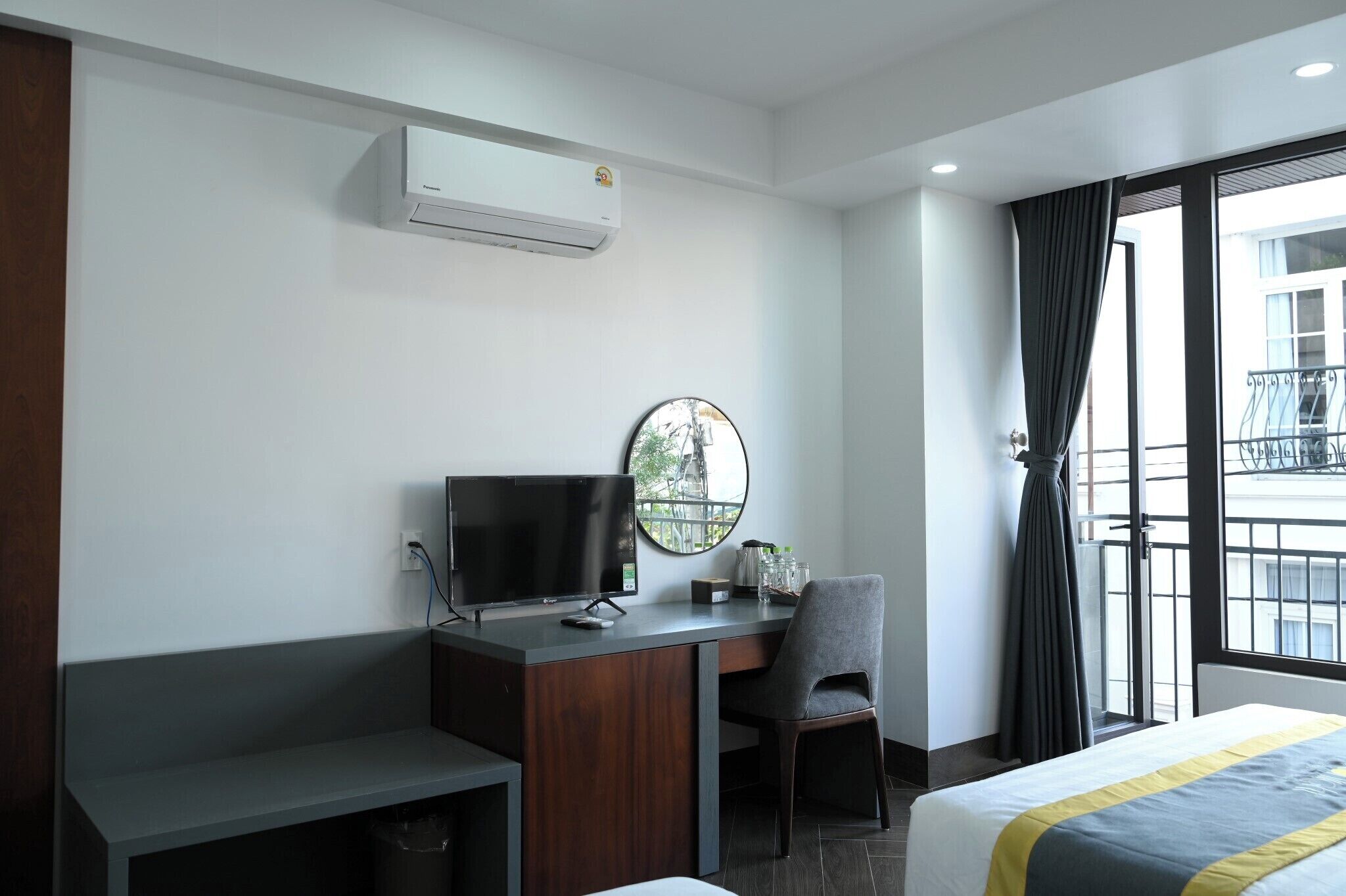 Une chambre d’hôtel équipée d’un bureau, d’une chaise, d’un lit et d’une grande fenêtre avec des rideaux.