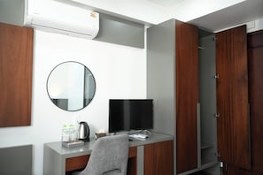 A modern hotel room with a desk, a flat-screen TV, a round mirror, and a wardrobe. - Moonlight Boutique Hotel (Hue)