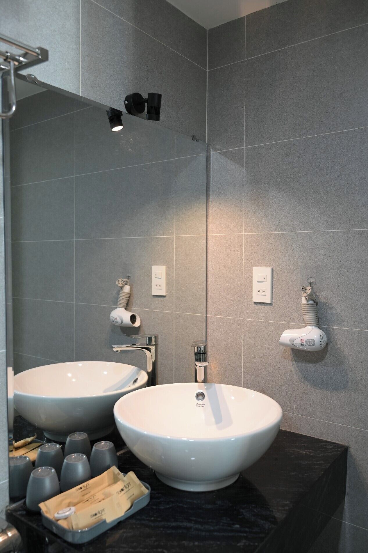 A modern bathroom with two large white sinks, a mirror, and a shower area.