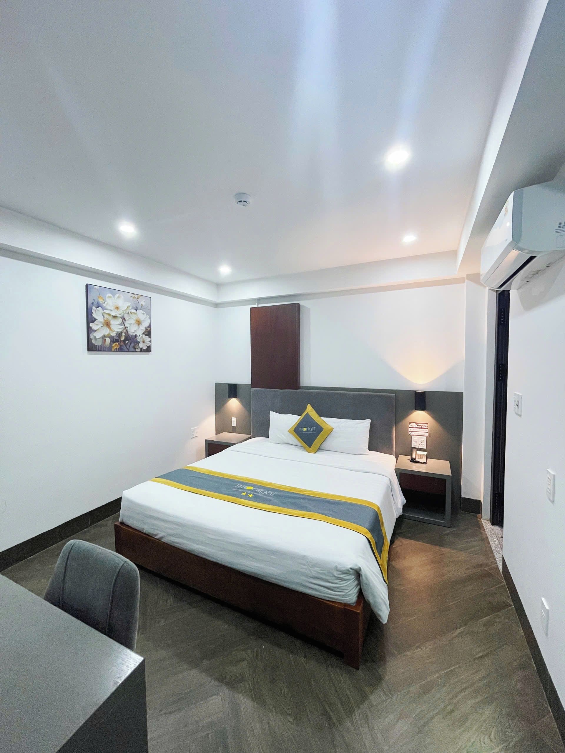 A hotel room with a bed, bedside tables, a desk, and a chair.