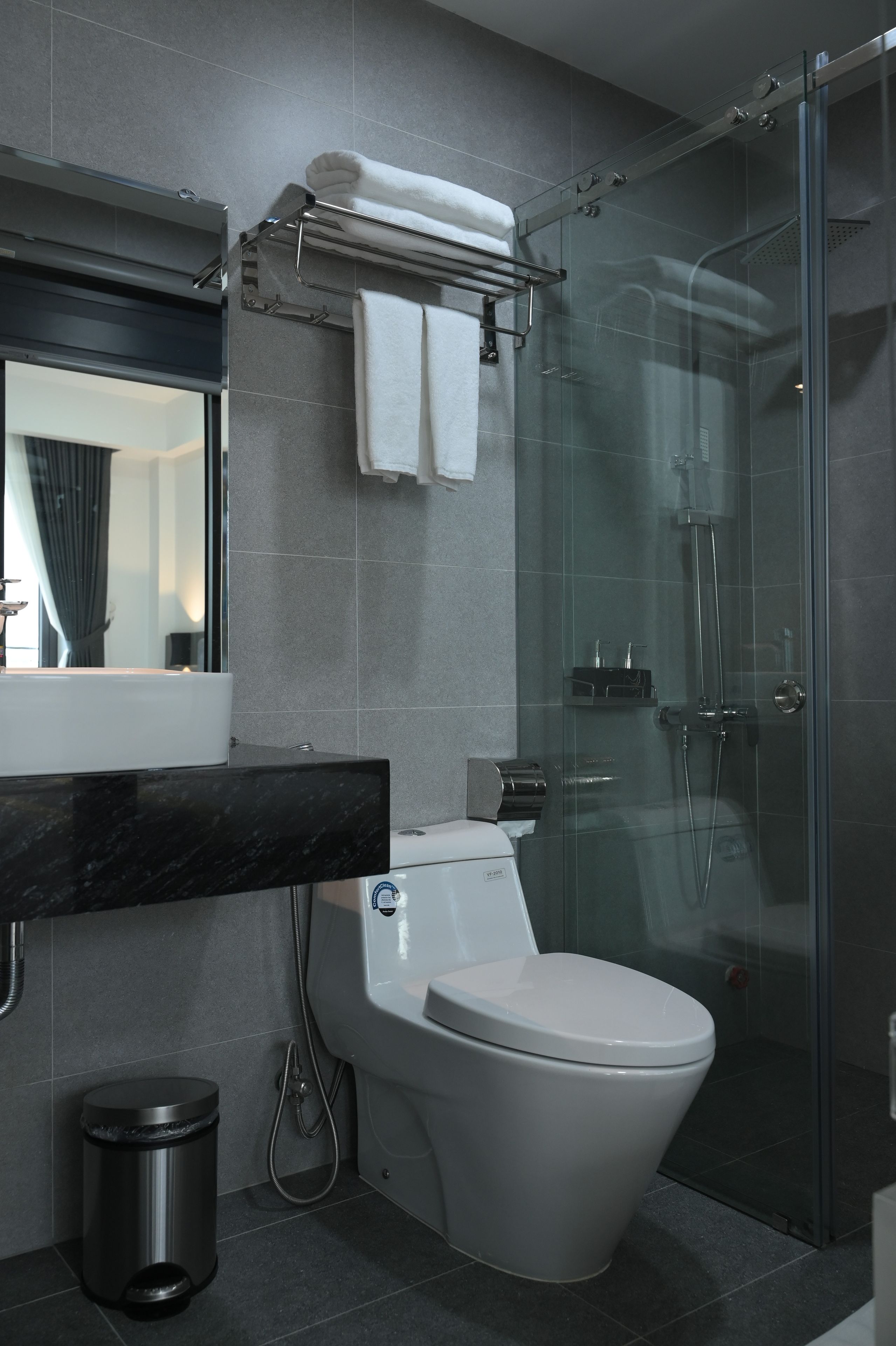Et moderne badeværelse med brusekabine i glas, toilet og vaskebord med spejl.